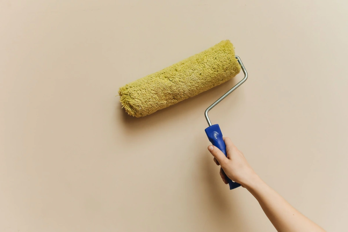 Application au rouleau d'une peinture claire sur un mur intérieur préparé