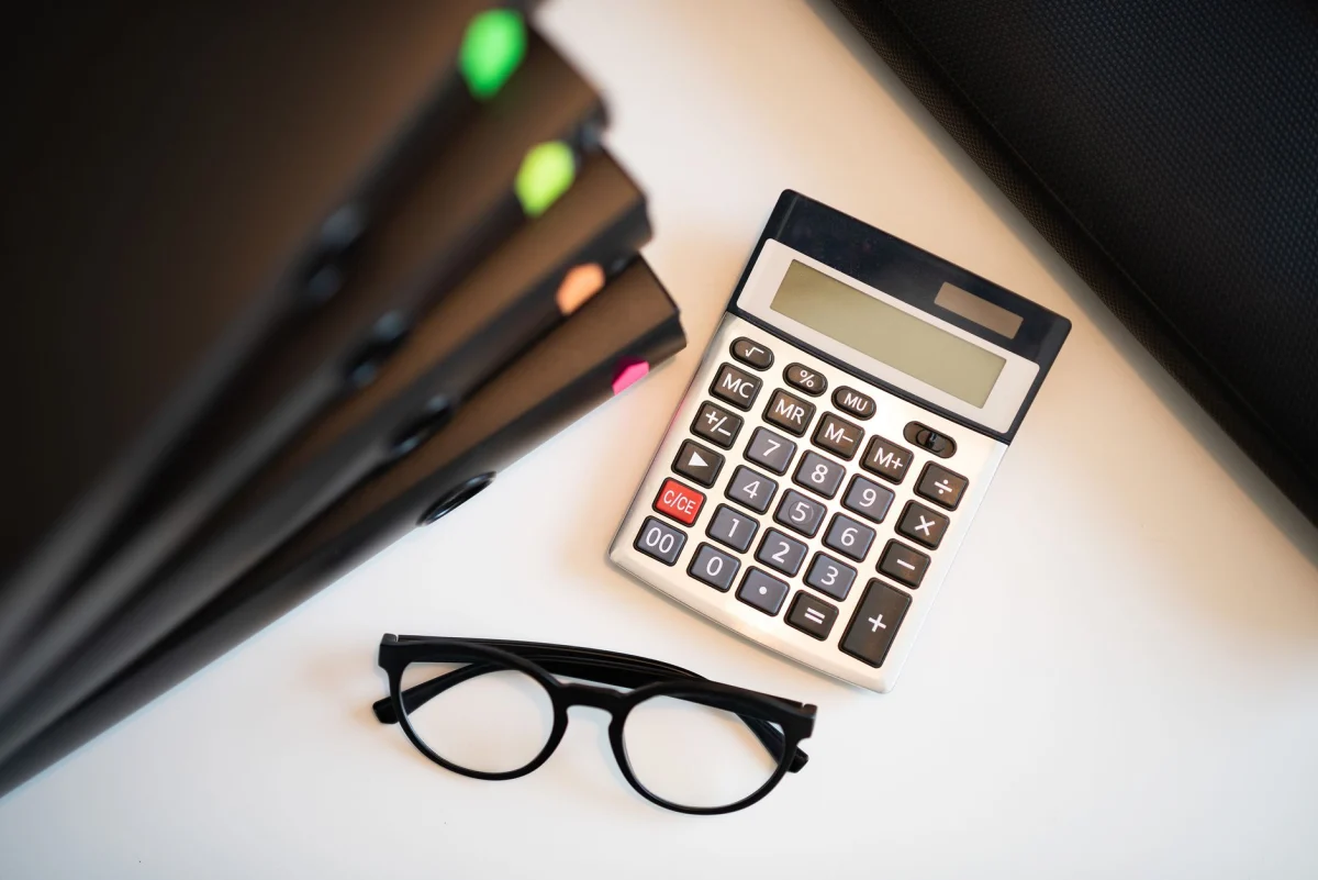 Plans et calculatrice posés sur une table pour l'estimation d'un chantier